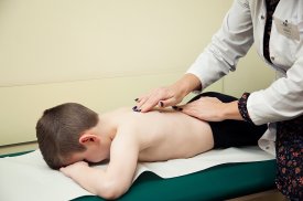Gydytoja apžiūri vaiko stuburą